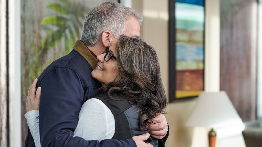 Middle aged couple hugging.