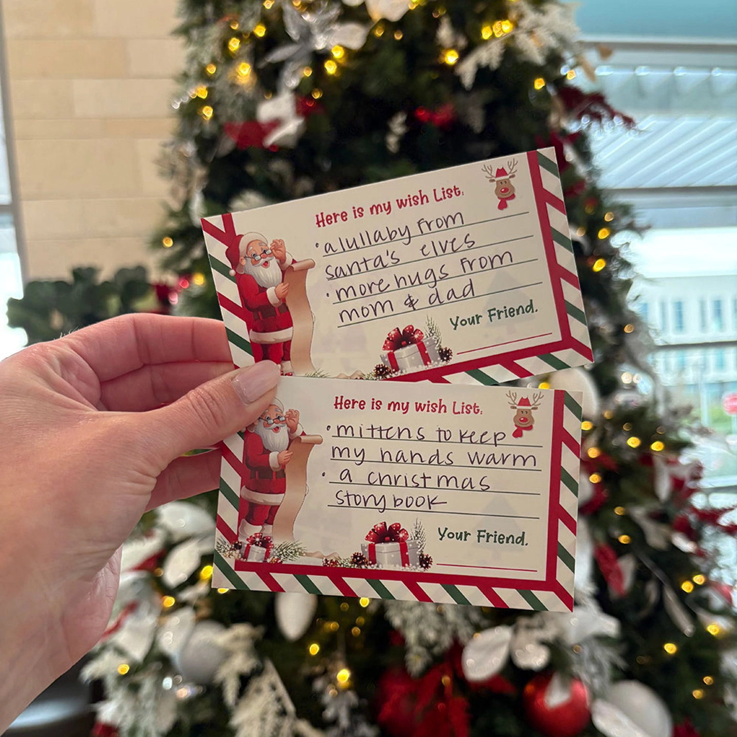 Hand displaying two babies' letters to Santa.