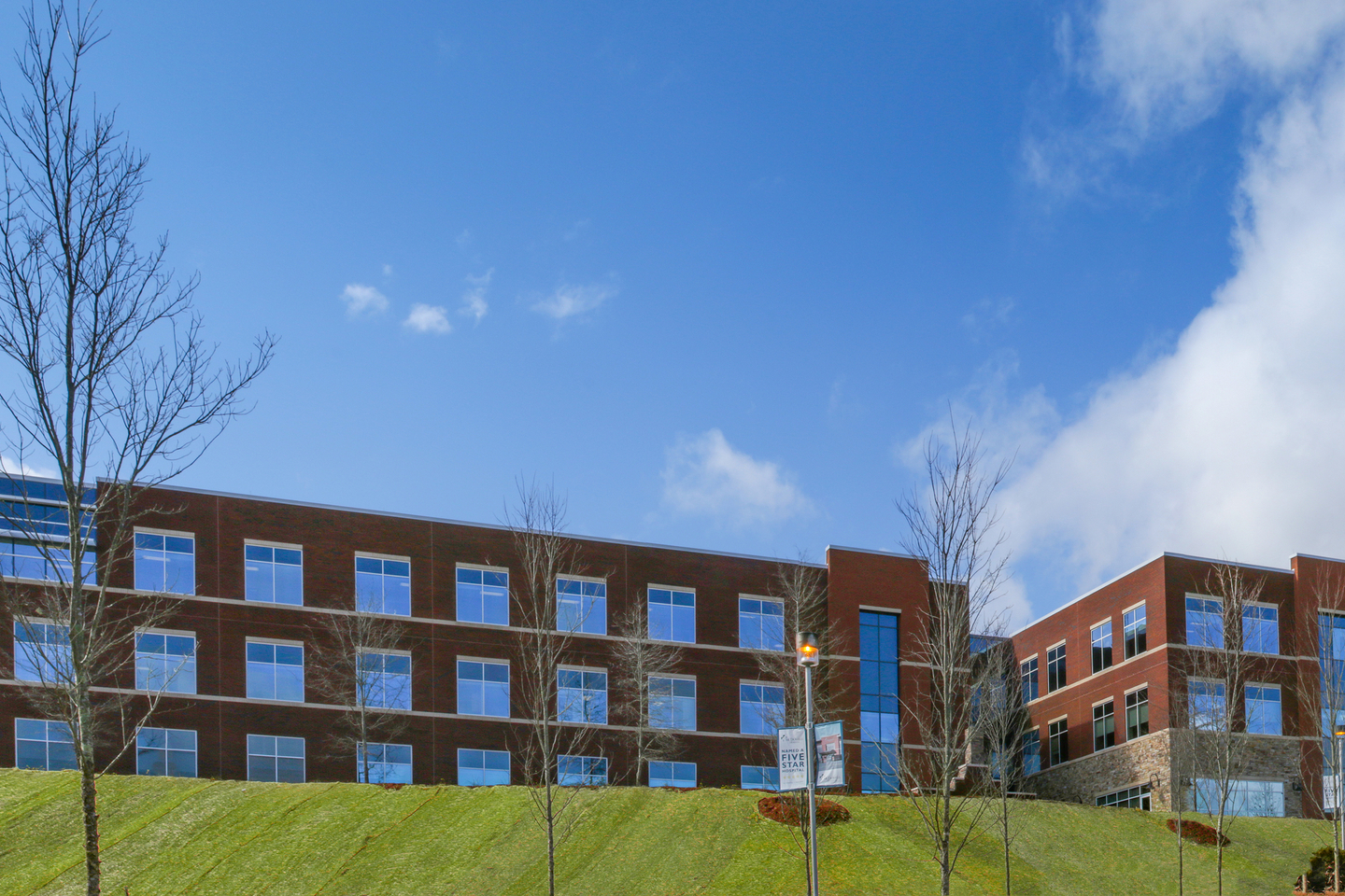 Exterior main entrance of the Mission Hospital McDowell facility on a clear day with a few clouds in the sky.