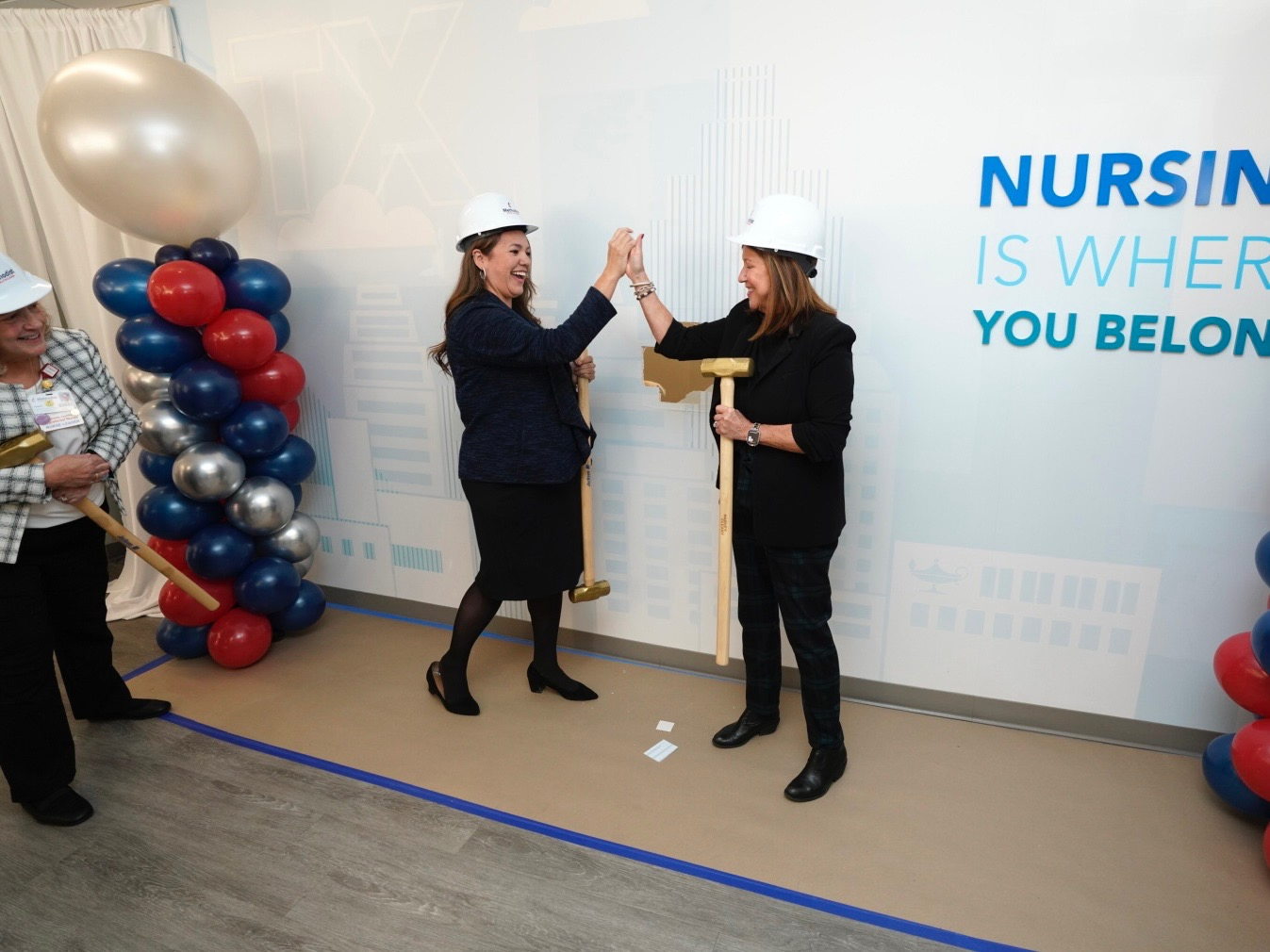 Colleagues celebrate together at the wall breaking ceremony for the simulation center renovation.