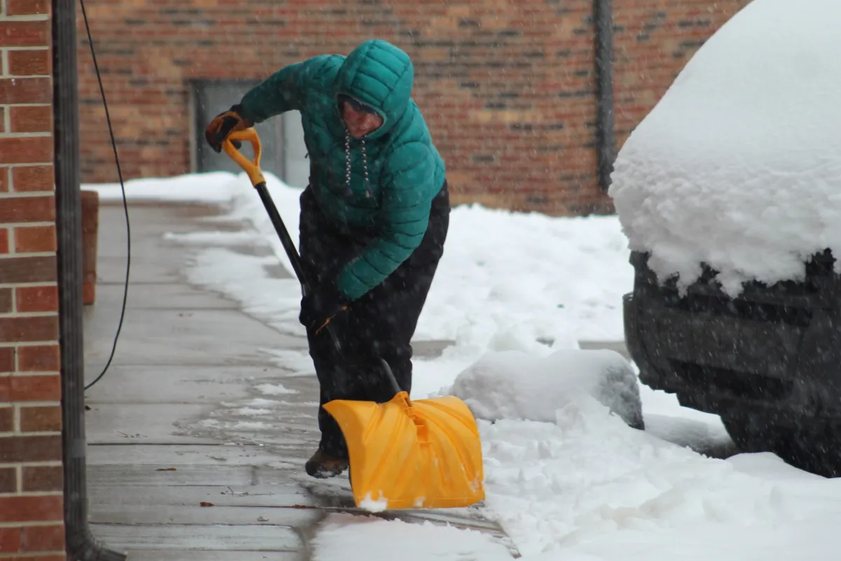 Person shoveling snow off a sidewalk.