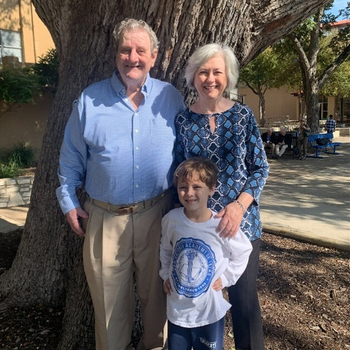 Robert, his wife, and his grandson stand and smile