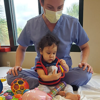 Enzo Rivera-Perez playing with toys with a nurse supervising him.