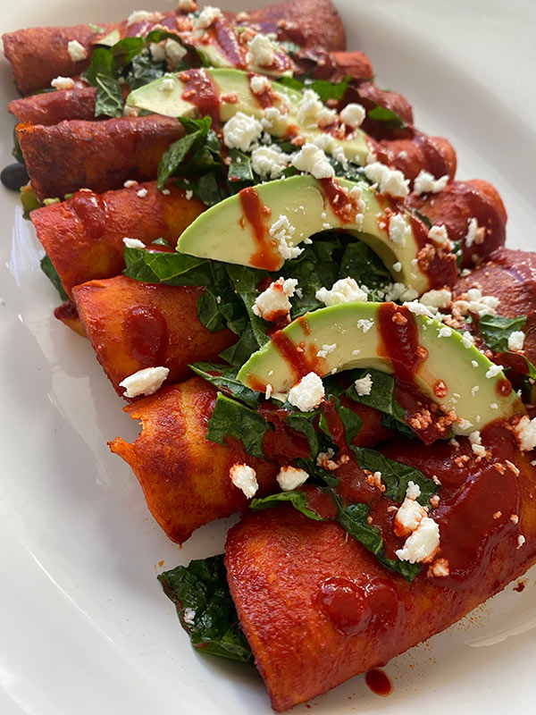 Healthy enchiladas with sliced avocados on top.
