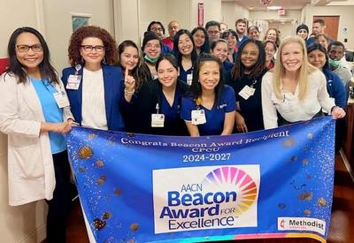 Methodist staff posing with AACN Beacon Award for Excellence banner.