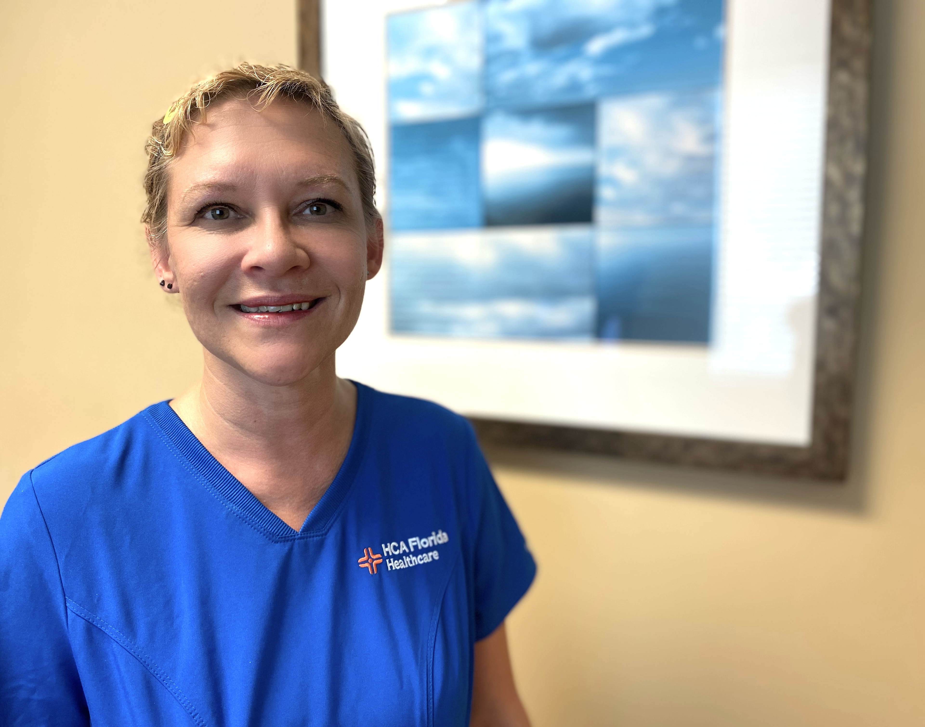 Susan Chiasson photo in blue scrubs next to abstract framed art