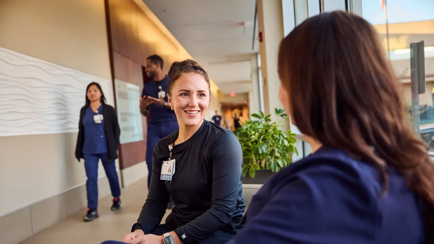 Two nurses having a conversation sitting on a couch
