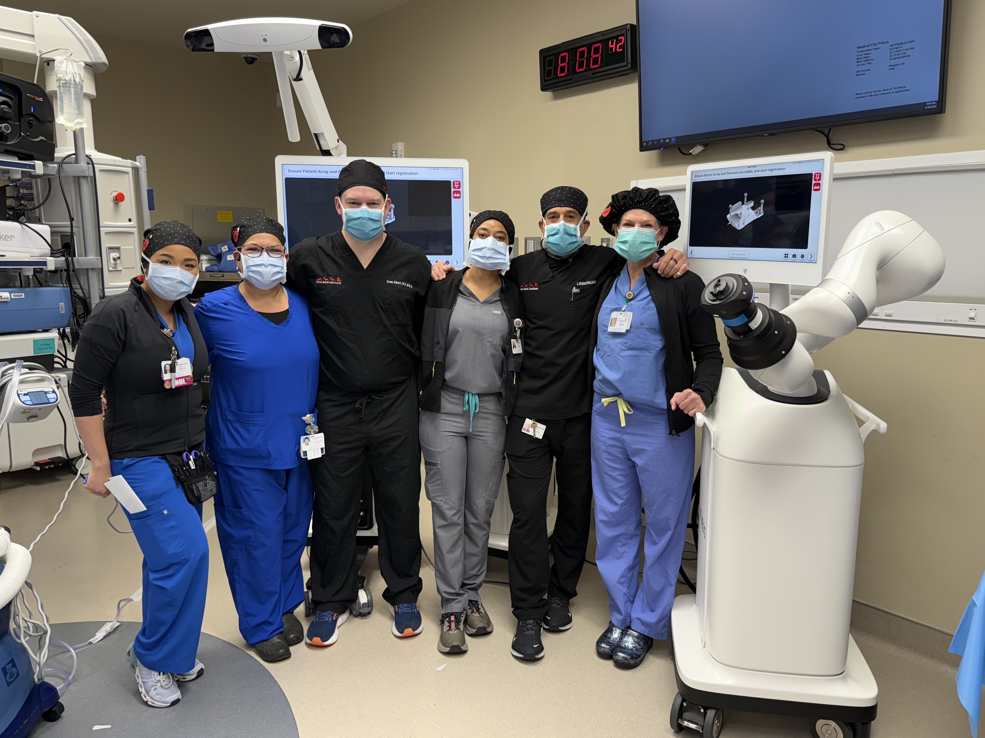 Medical City Frisco robotic surgery team posing in room with surgery robot