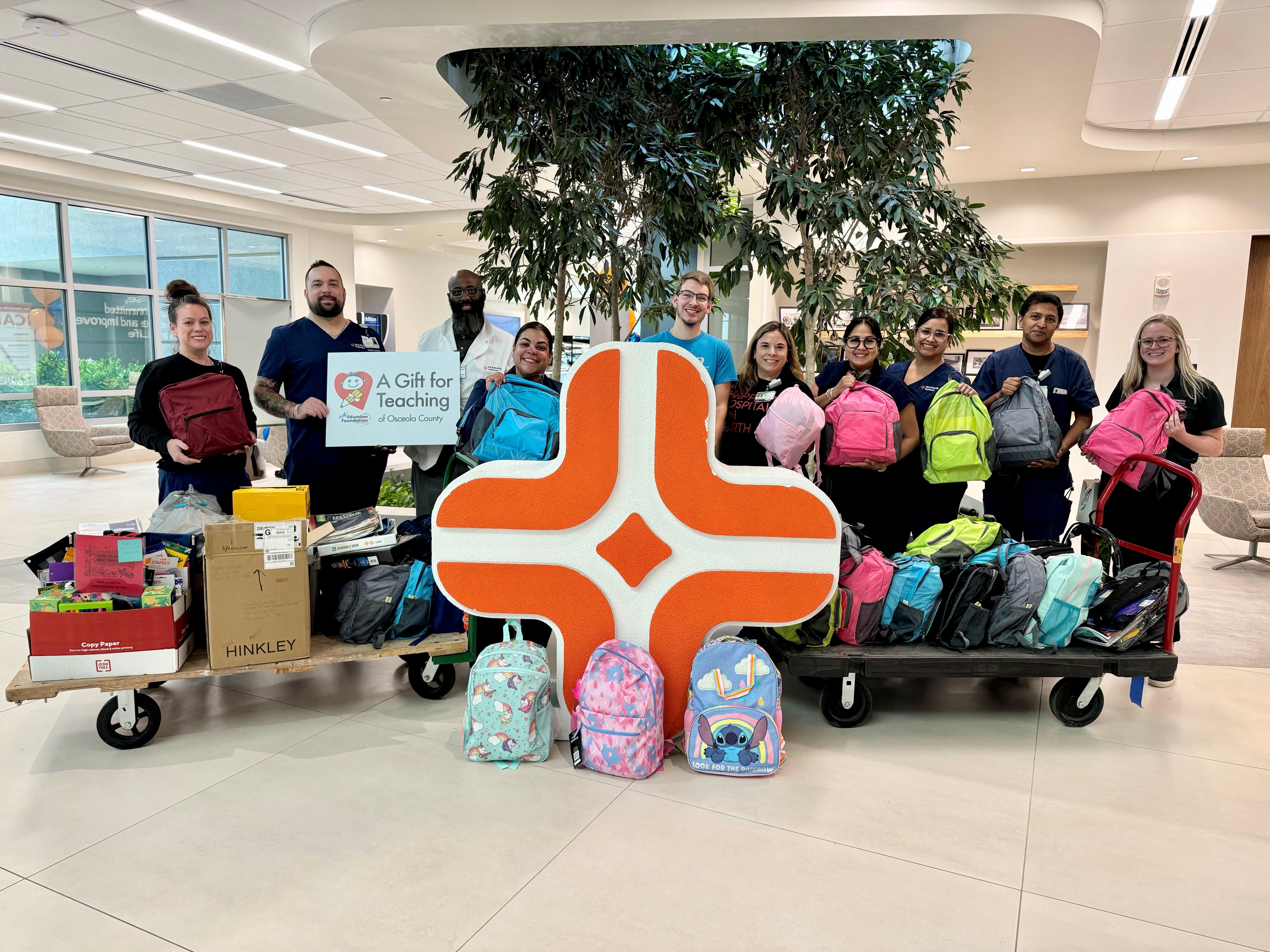 group of hospital staff with school supply drive items, holding backpacks