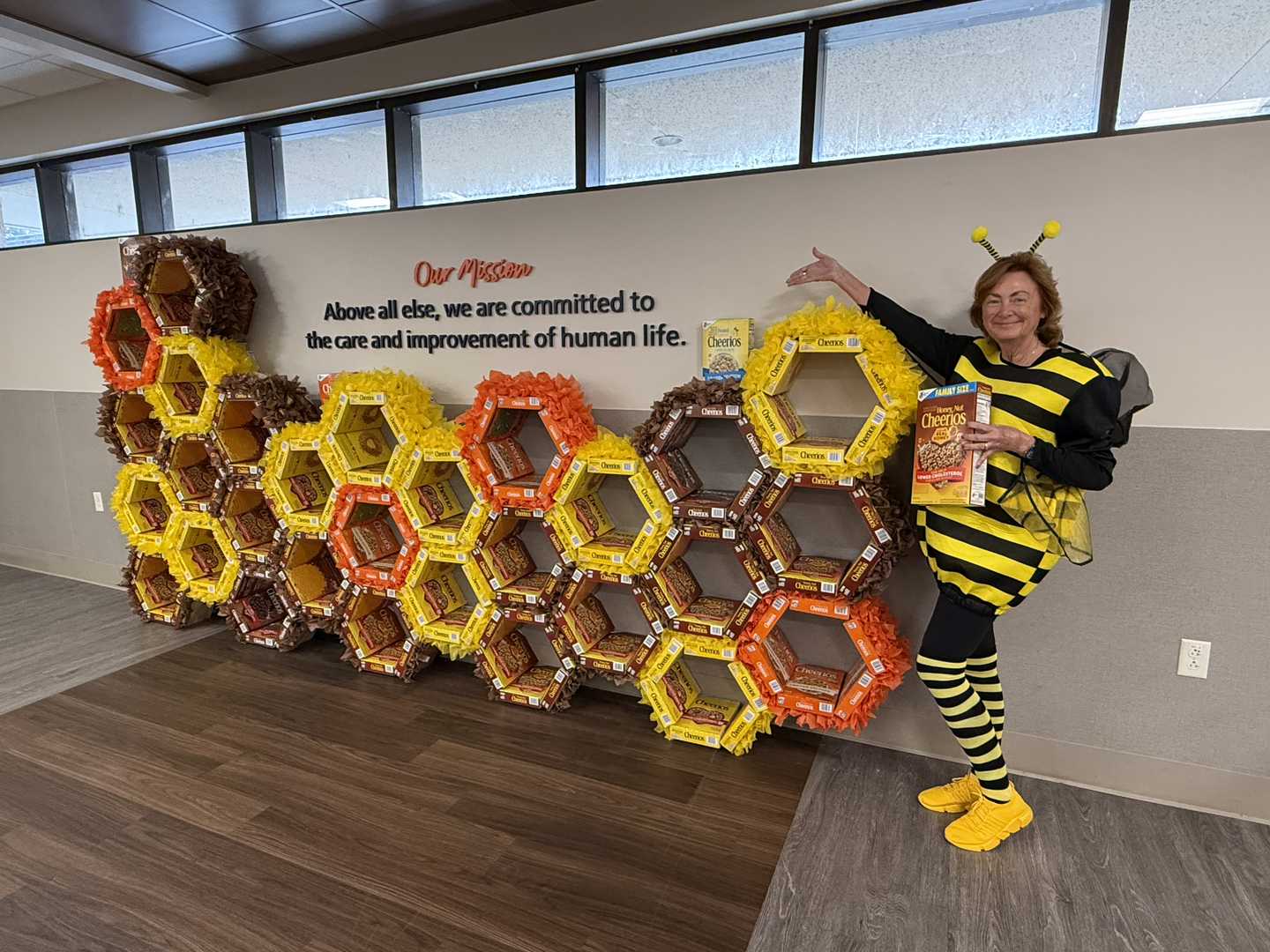 A woman with a bee outfit poses next to a presentation for the event.