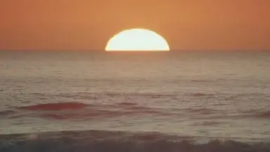 The sun rising over the sea.