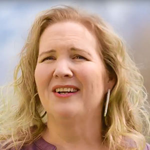 Jennifer discusses her surgery at St. Mark's Hospital, and is wearing earrings and a purple blouse.