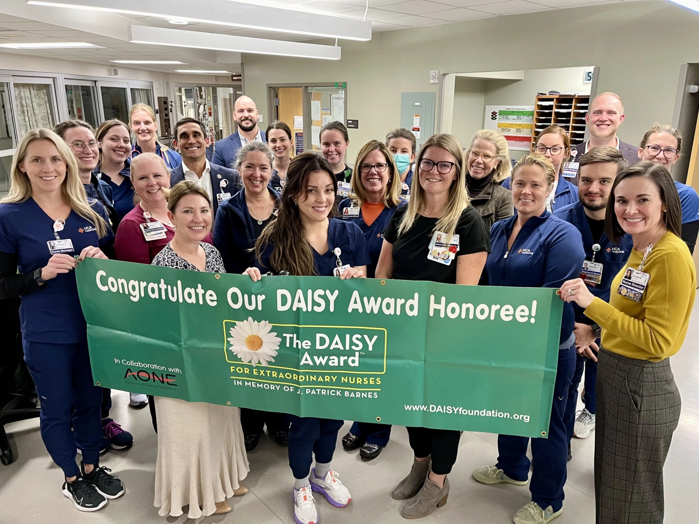 Lauren Morelli and her team hold a banner congratulating her for being a daisy award honoree