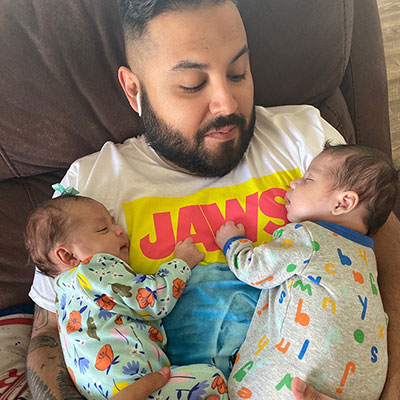 Isaac gingerly holding his newborn twins.
