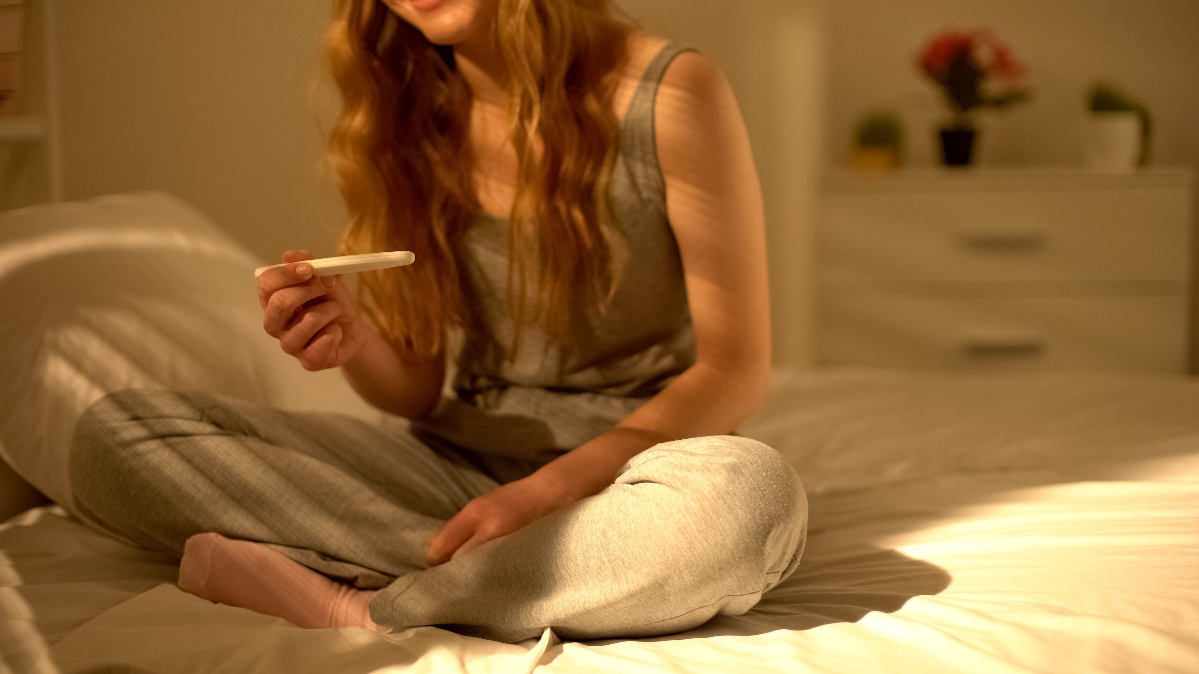 Young woman holding a pregnancy test and looking at the results.