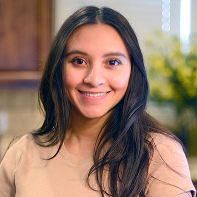 Kayleigh Williams smiles for the camera while standing in her kitchen.