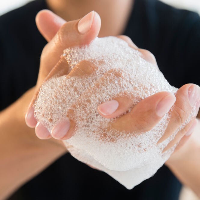 Person washing hands with soapy water.
