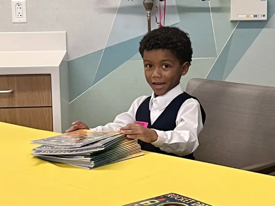 Young boy Payton seated at table with books.