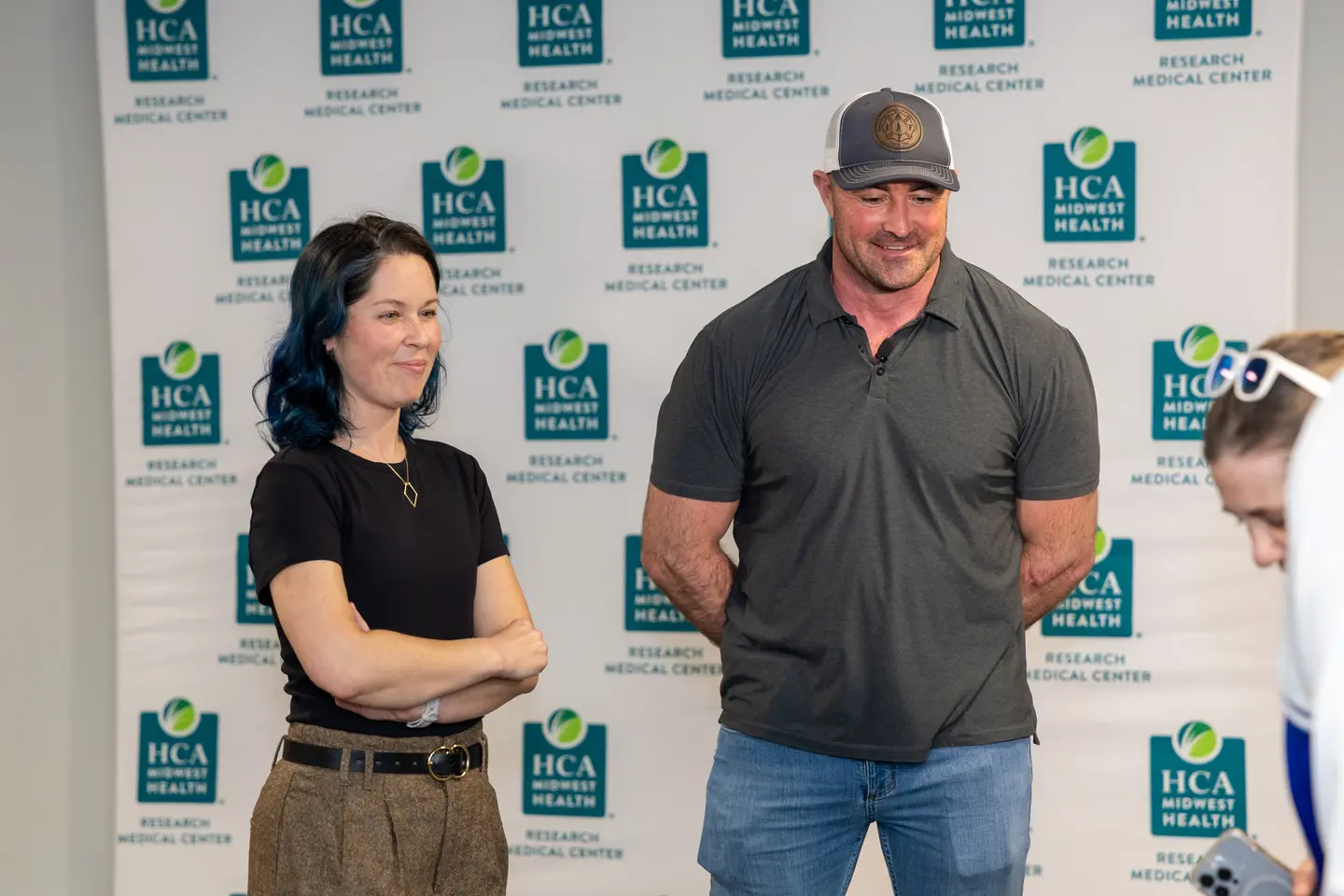 Two individuals standing outside in front of a HCA Midwest billboard celebrating.