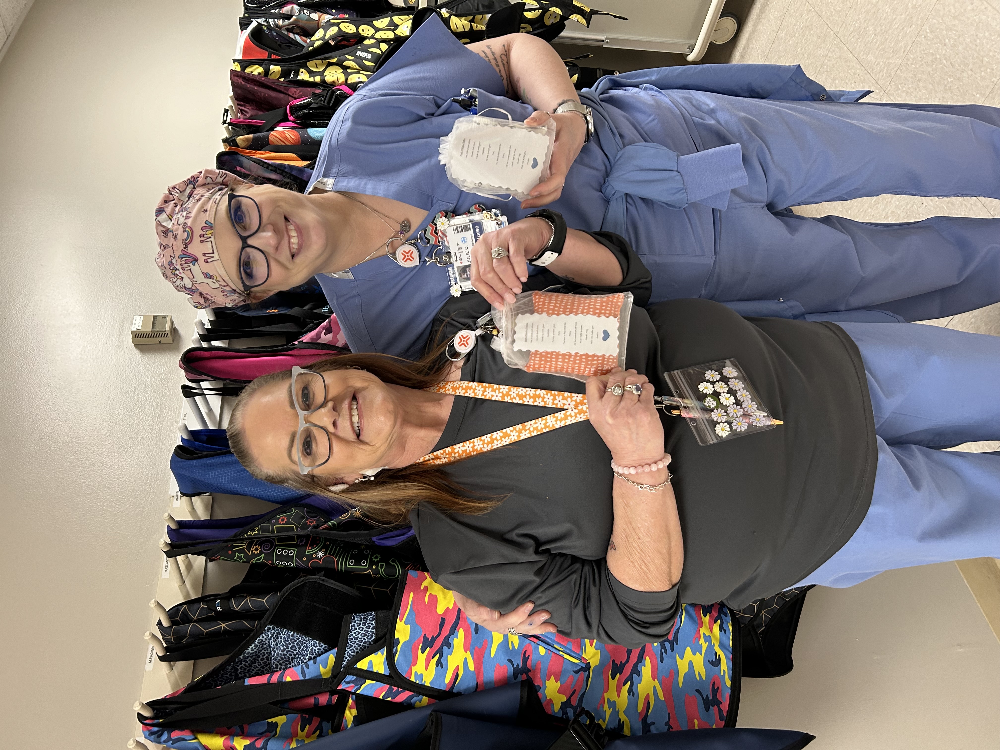 Two female nurses holding the handmade pillows, smiling and posing for photo.