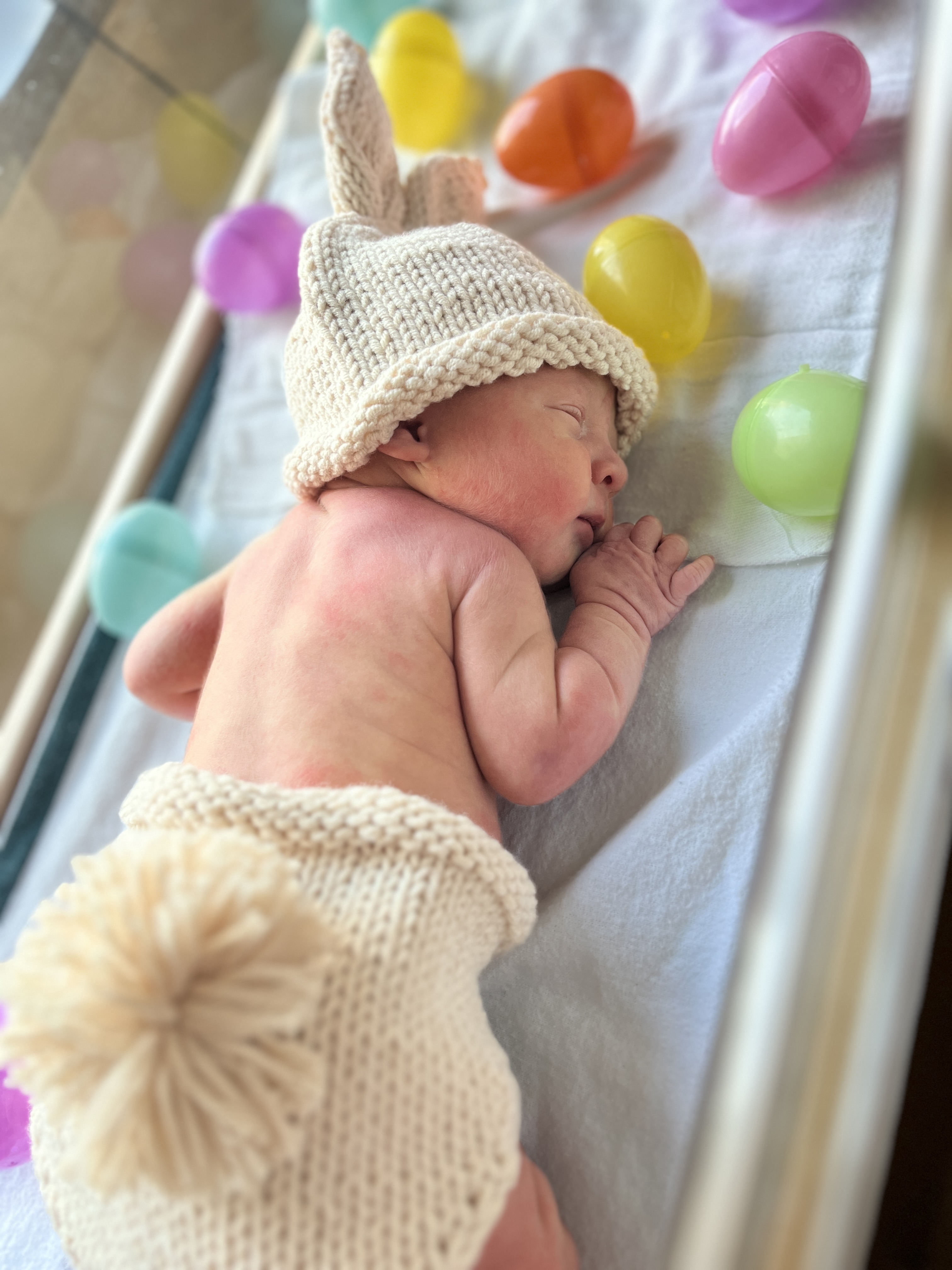 Newborn baby in hospital crib in a bunny costume.